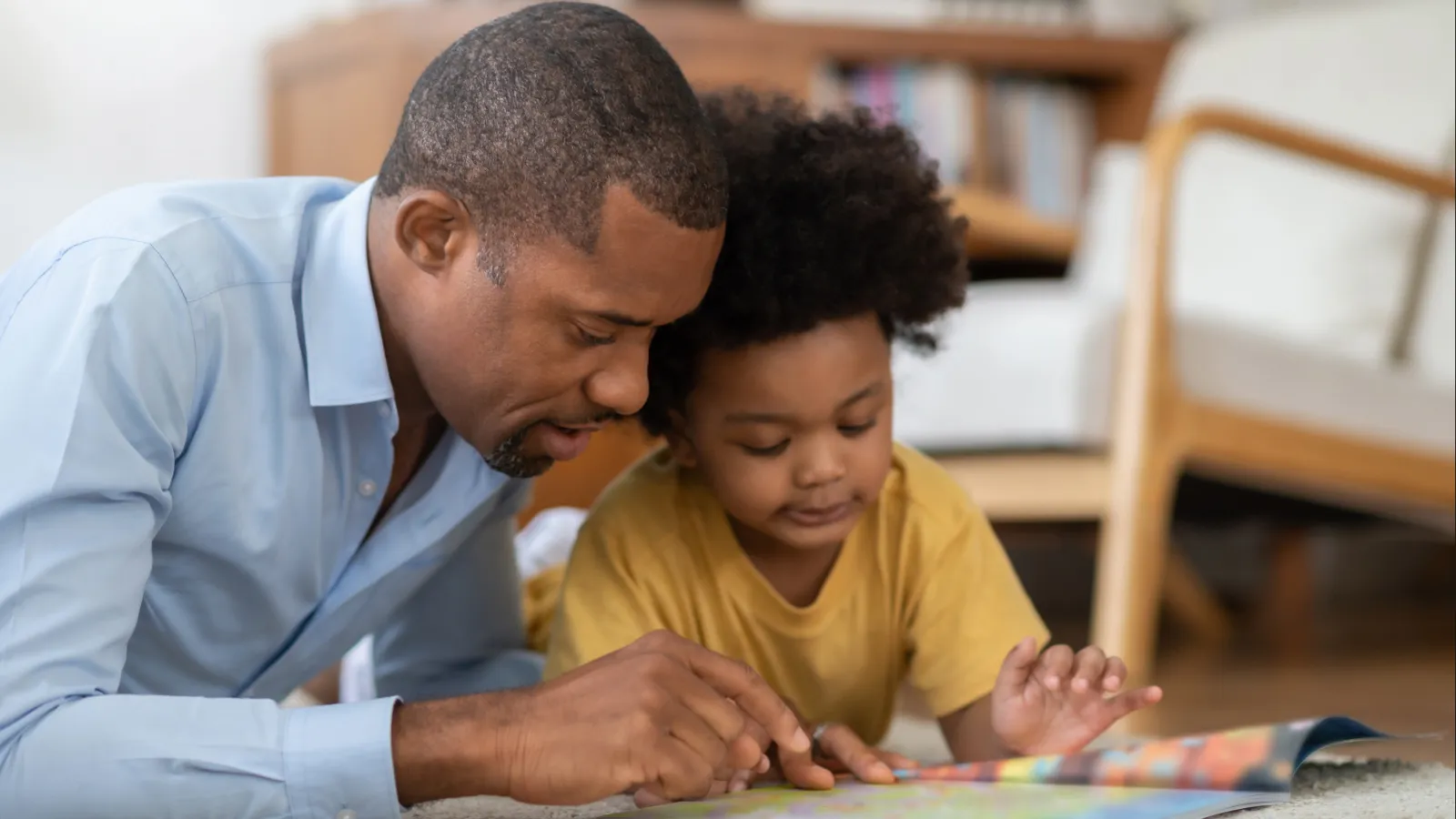 Father and his young son boy reading a book together