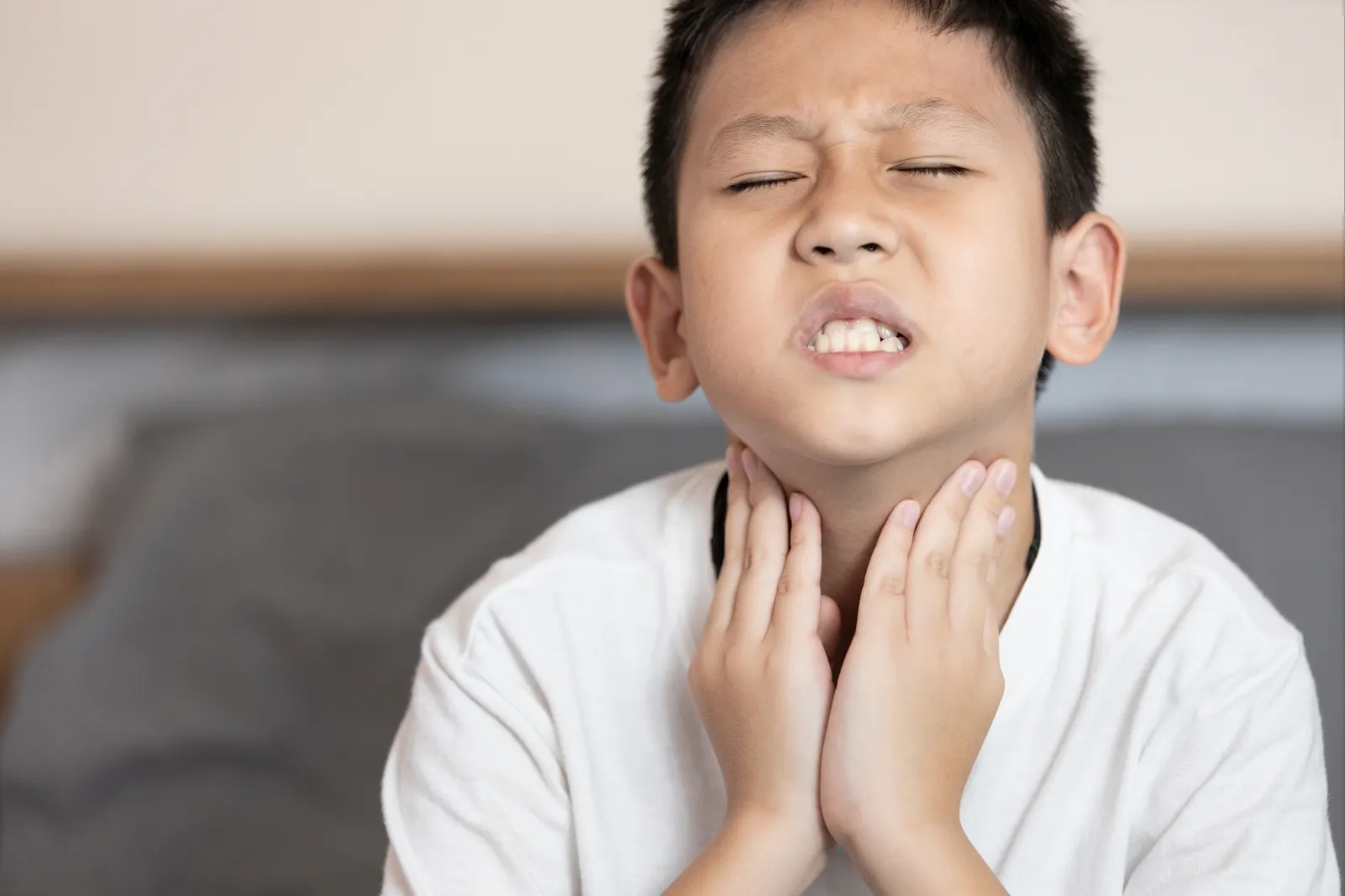Boy touching his neck